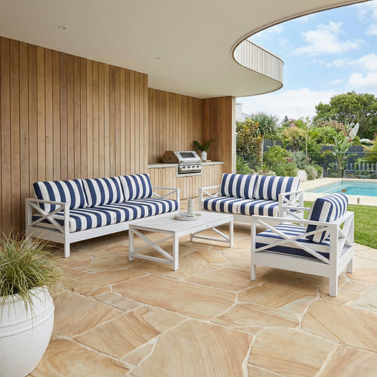 White outdoor lounge set with blue striped fabric cushions on a patio.