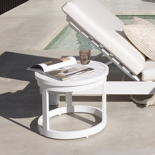 White outdoor side table beside a pool sunlounger.