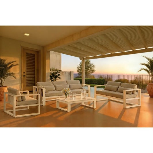 White outdoor lounge set with cushioned sofa, armchairs, and a coffee table on a covered patio at sunset, overlooking a scenic landscape.